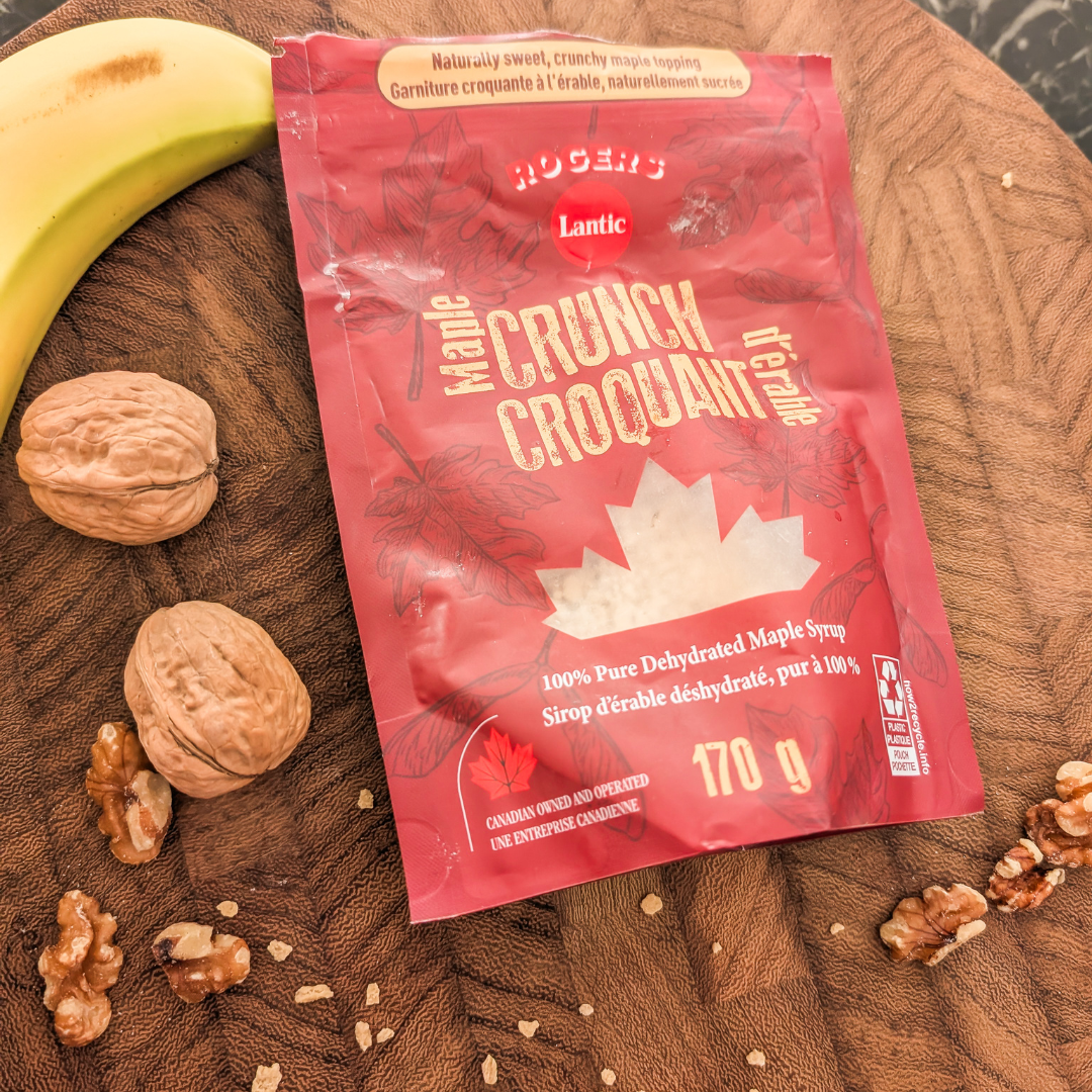 Maple Crunch syrup packet on wooden surface with walnuts and banana.