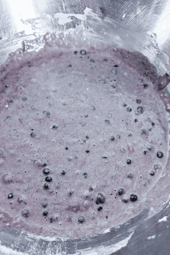 Blueberry muffin batter with frozen Canadian wild blueberries in a mixing bowl.