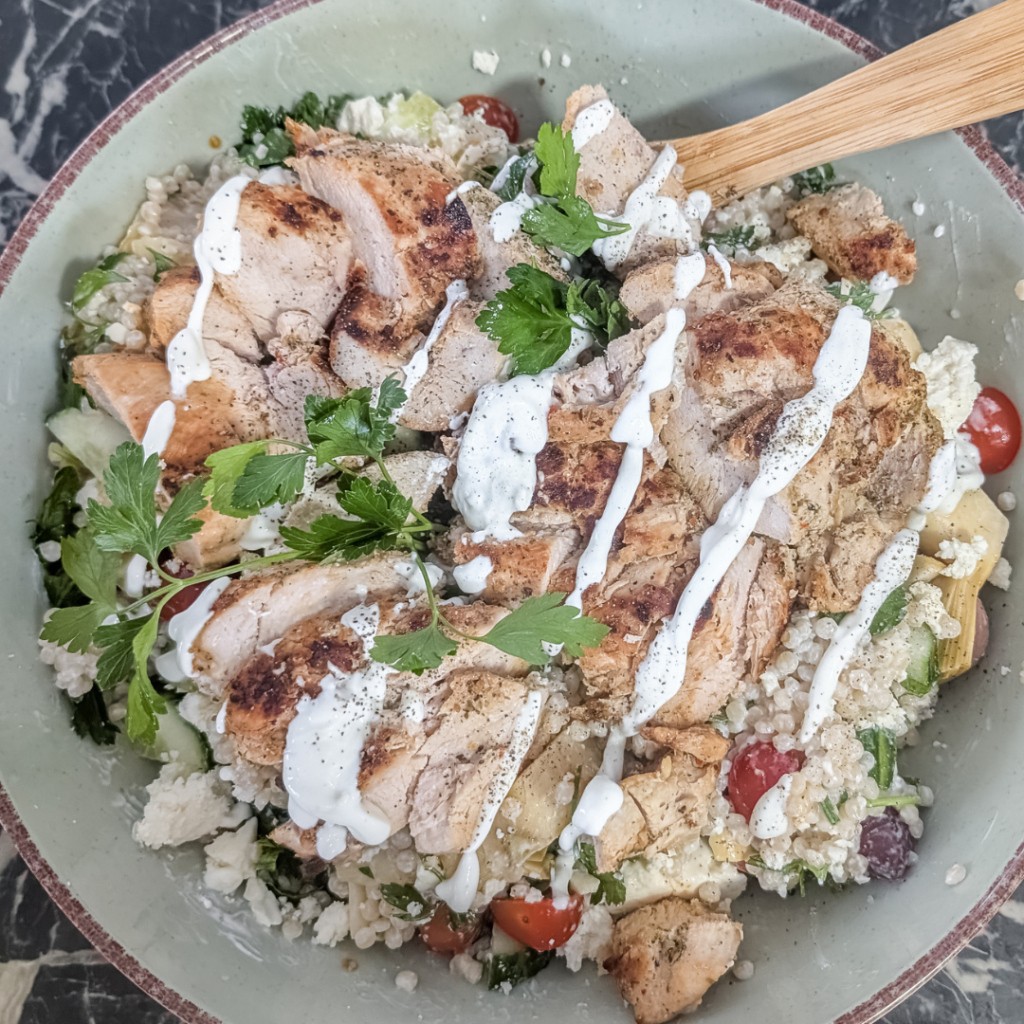 Chicken couscous salad topped with Greek yogurt dressing and fresh herbs.