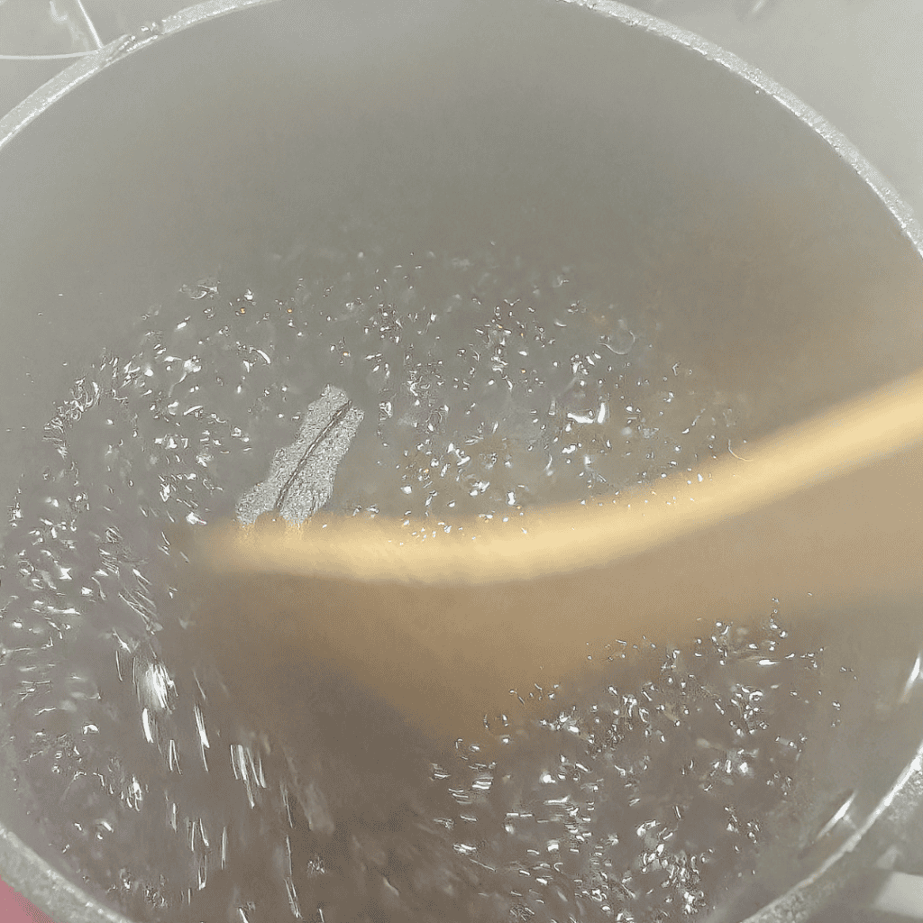 Boiling blueberry mixture for ice cream with reduction in a pot.