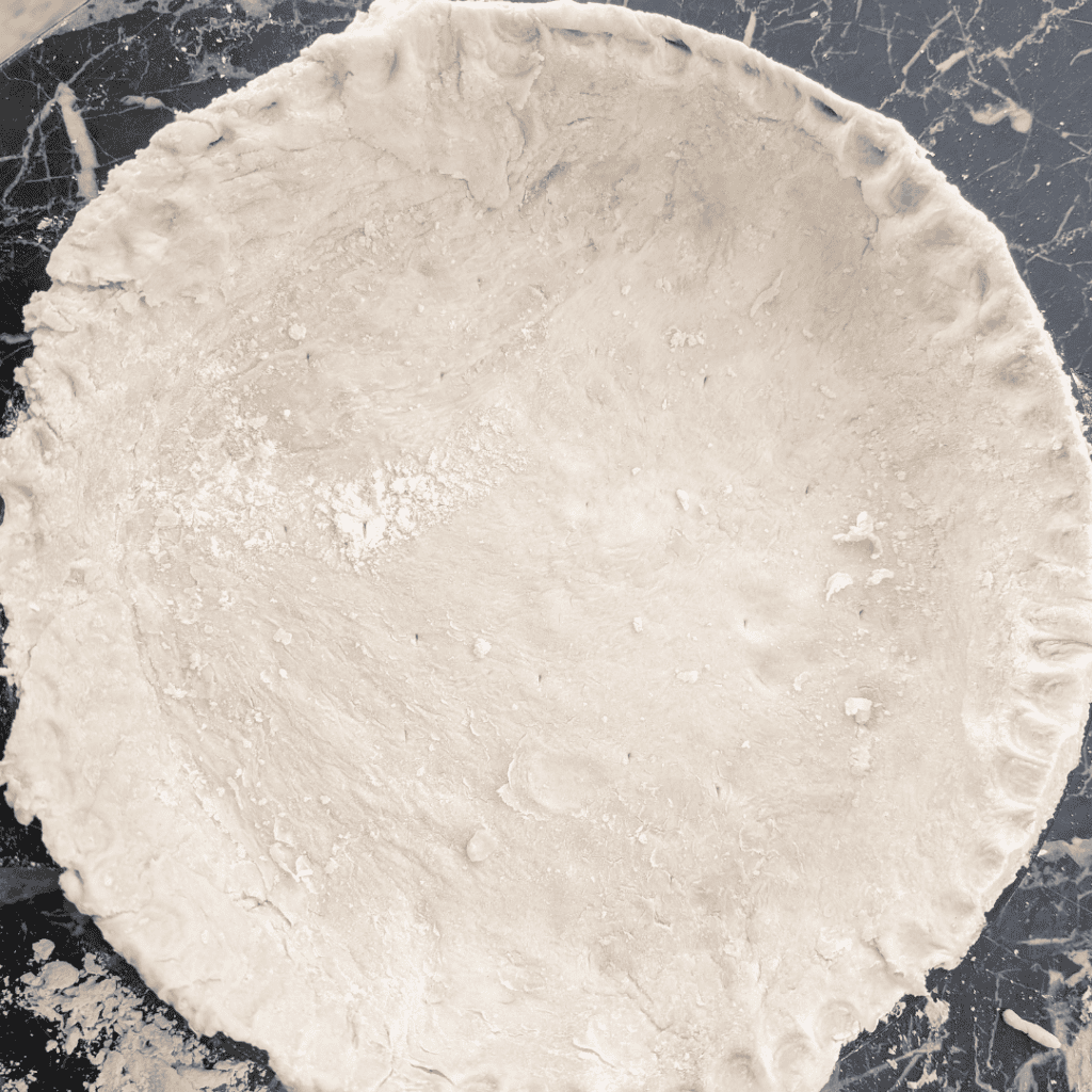 Unbaked pie crust with dough for ham and asparagus quiche, ready for baking.