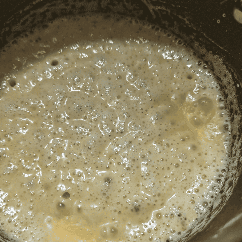 Thick and creamy cheddar cheese sauce in a pan, perfect for burgers.