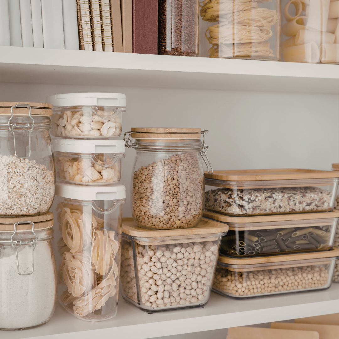 Pantry with glass jars filled with grains, pasta, and legumes for storage.