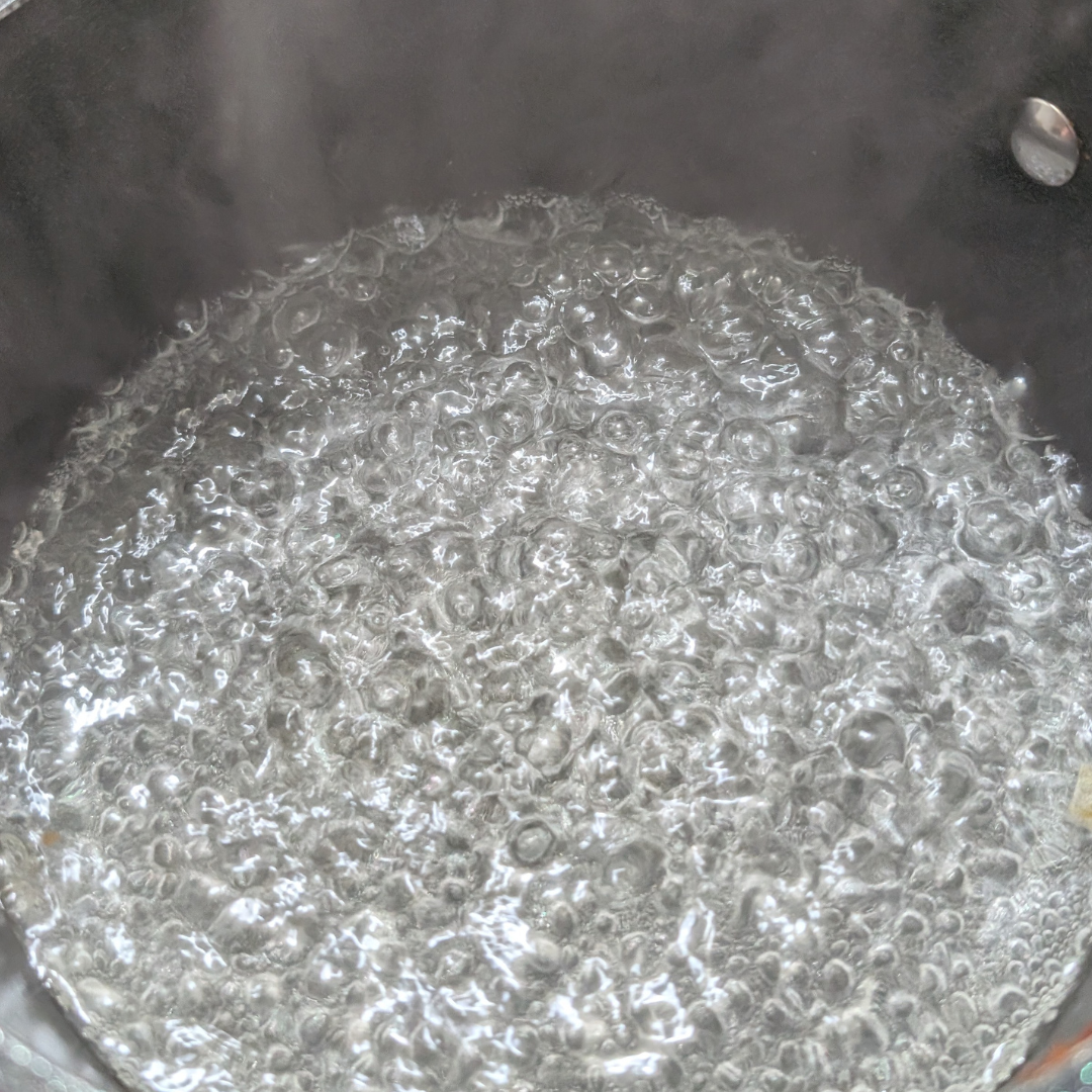 Boiling water with vigorous bubbles indicating a rolling boil.