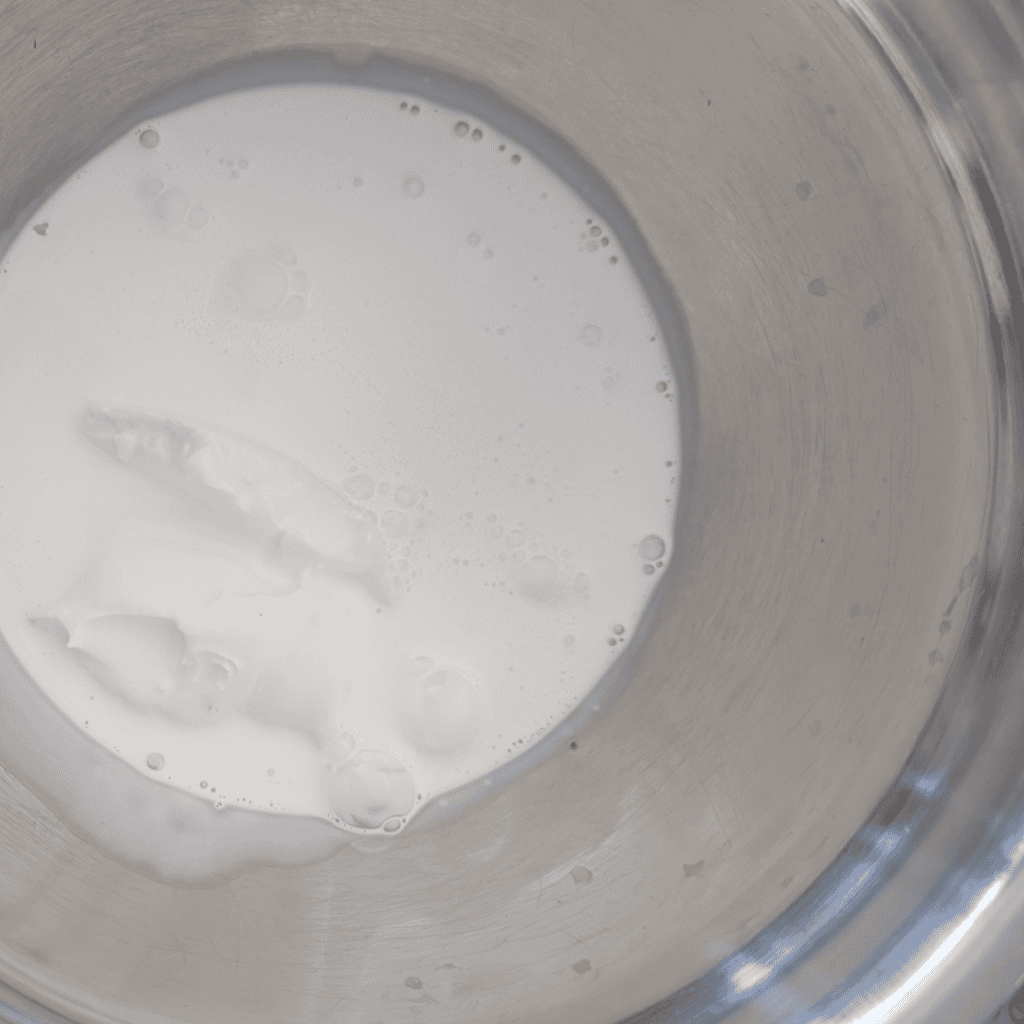 Blueberry ice cream mixture with reduction in a metal bowl.