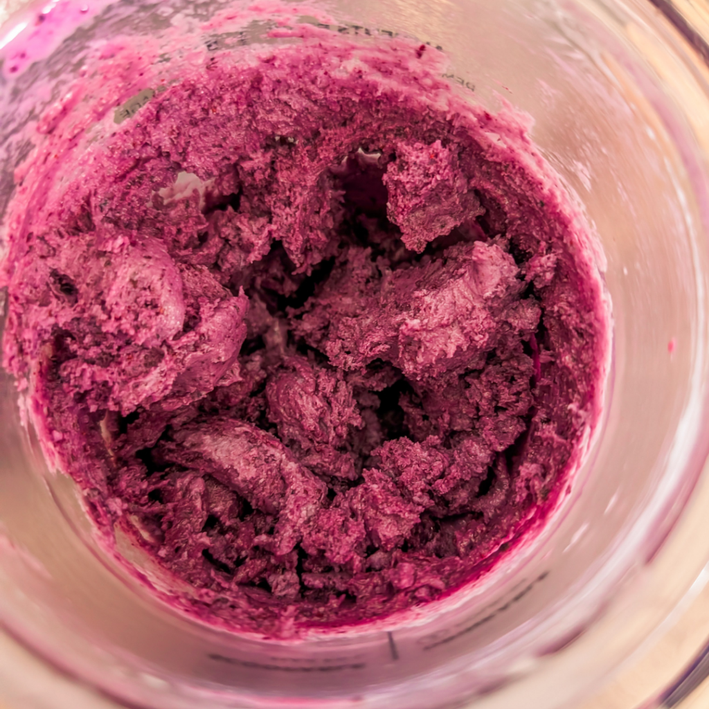Close-up of vibrant blueberry ice cream with blueberry reduction topping.
