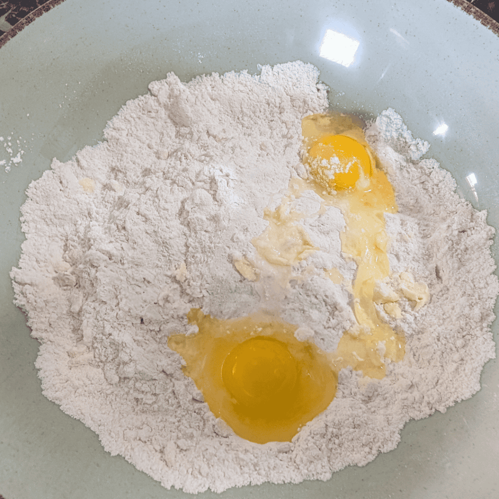 Flour and eggs in a mixing bowl for baking or cooking.