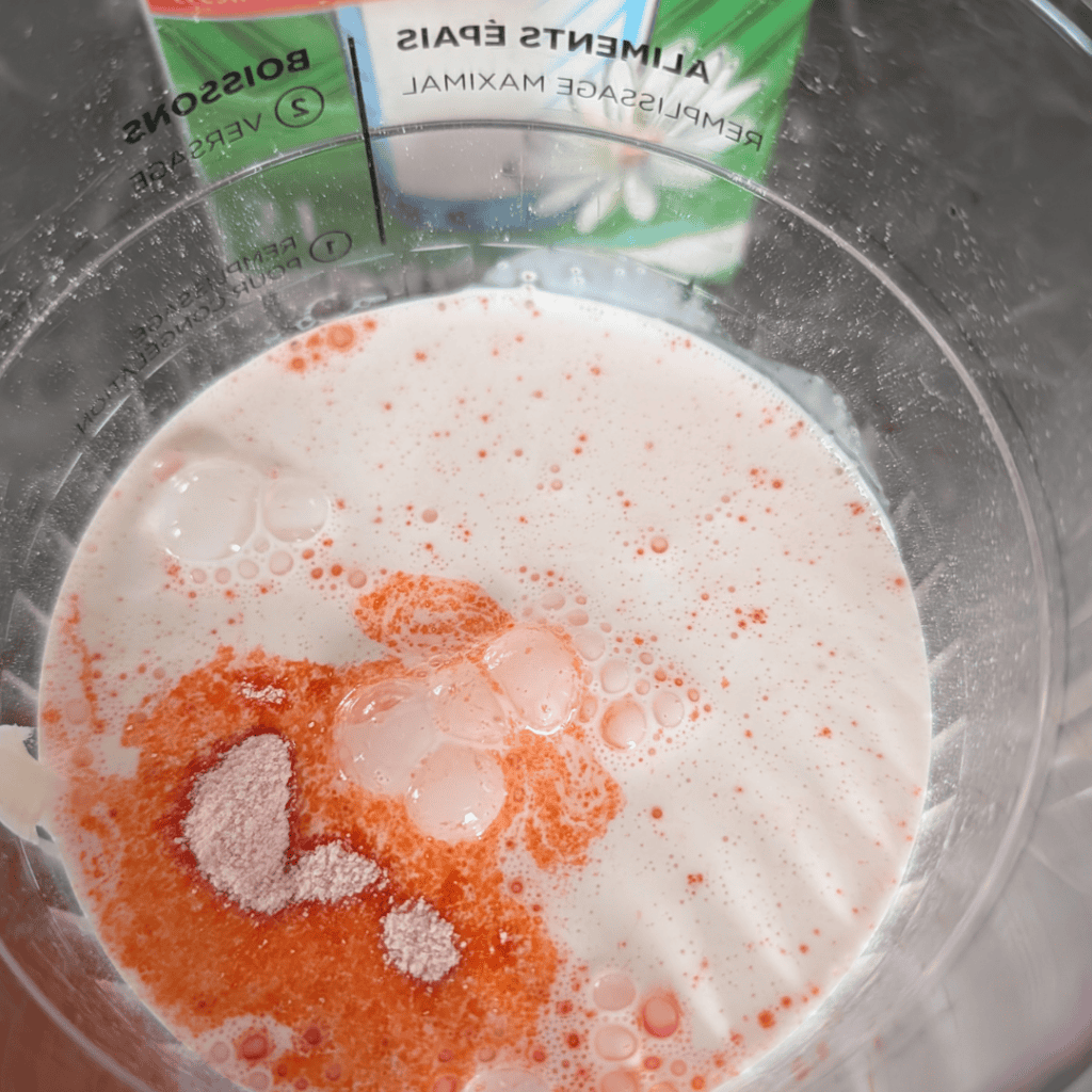 Blended orange creamsicle ingredients in a Ninja Creami for homemade ice cream.