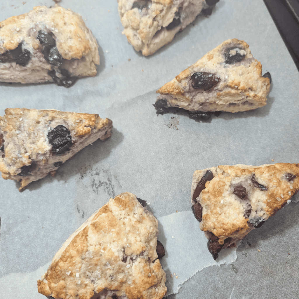 Freshly baked chocolate chip scones with berries on parchment paper.