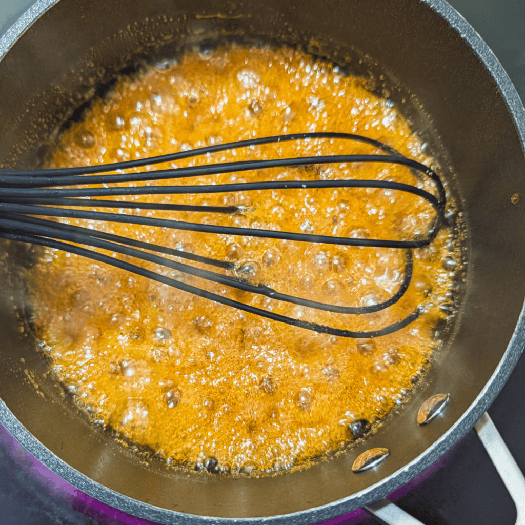 Cooking maple glaze in a pan with a whisk for ribs.