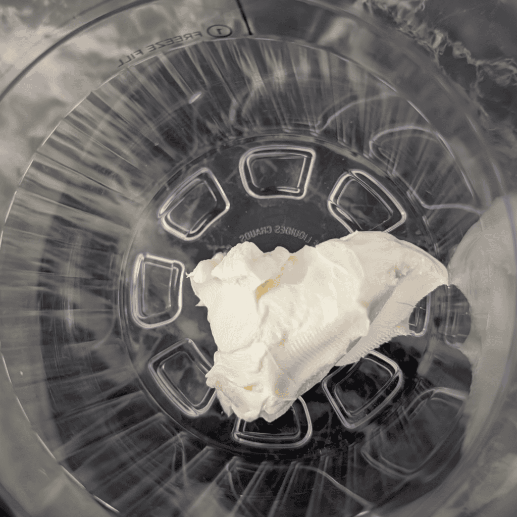 Creamy orange creamsicle ice cream in a Ninja Creami container, ready to freeze.