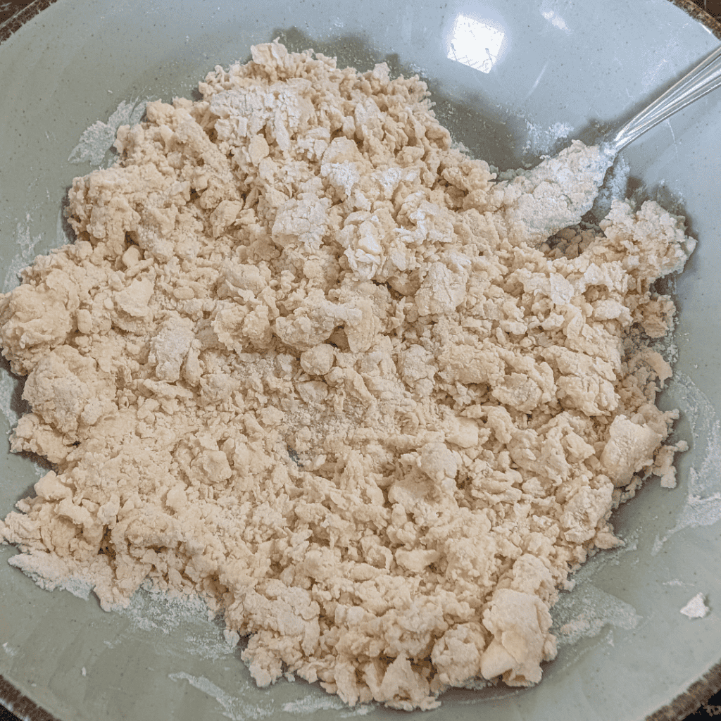 Crumbled dough mixture in a bowl for baking or cooking.