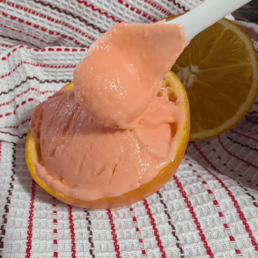 Orange Creamsicle Ninja Creami Ice Cream in a halved orange with a spoonful served.