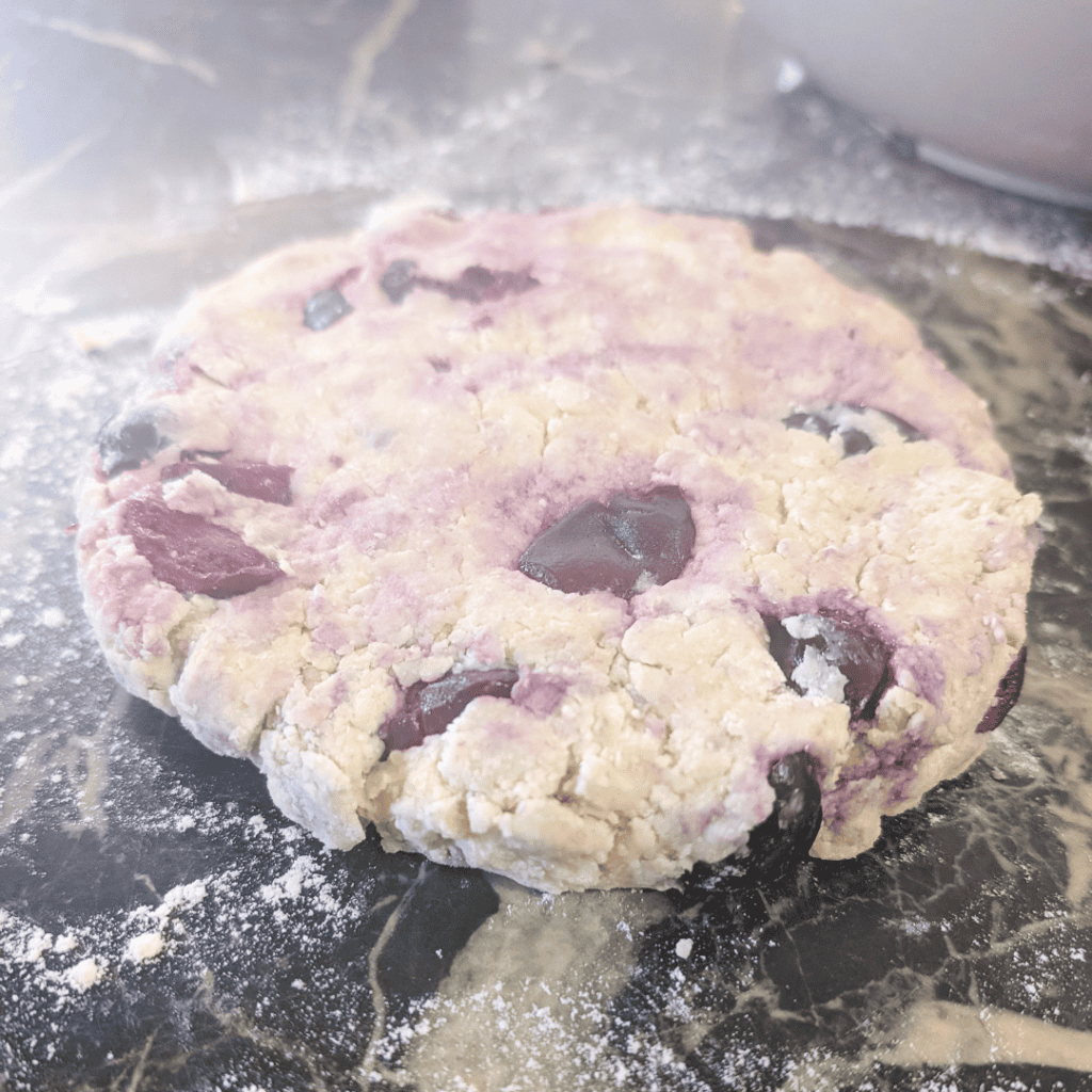 Freshly prepared chocolate chip cookie dough ball on a floured surface.