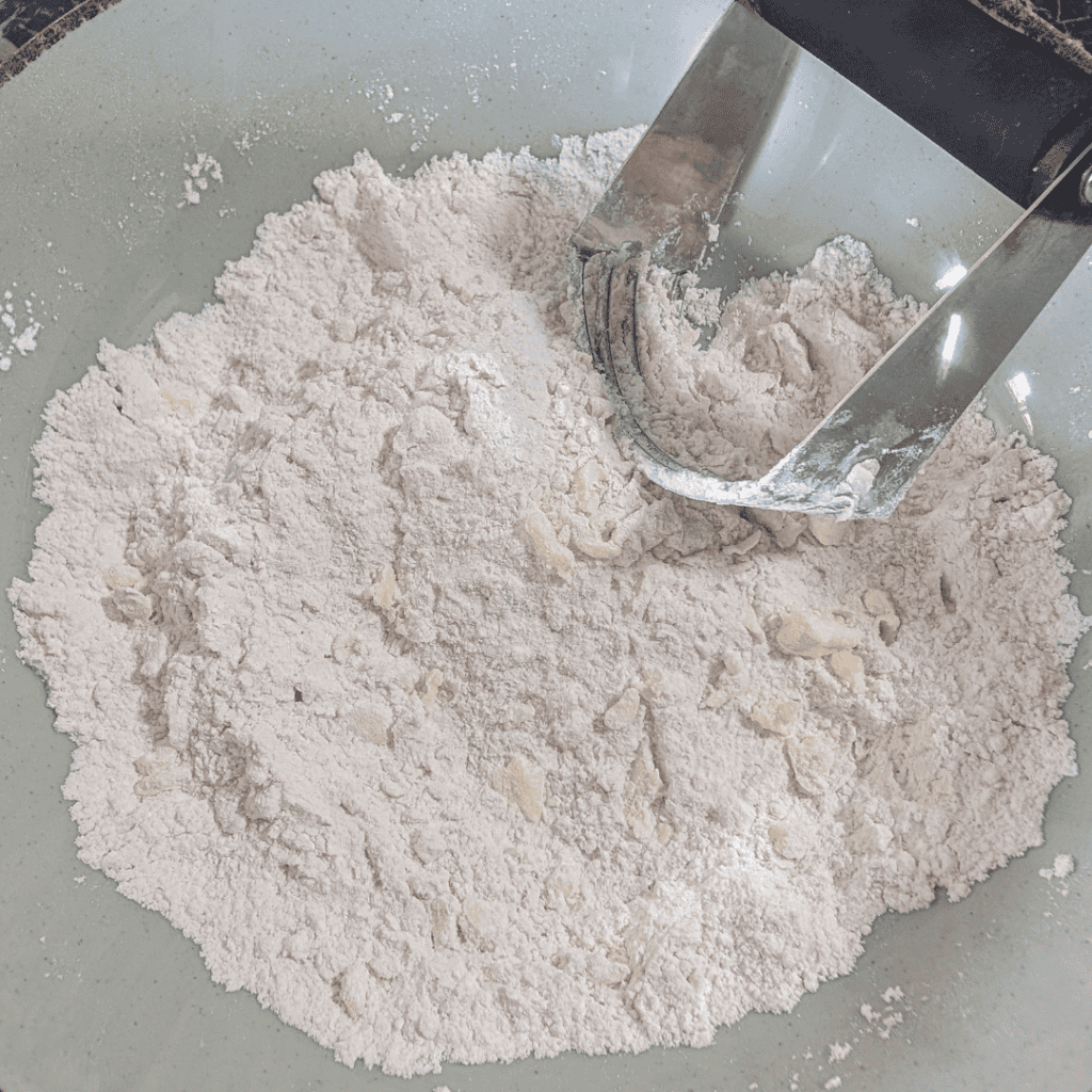 Flour being sifted with a pastry cutter for baking preparation.