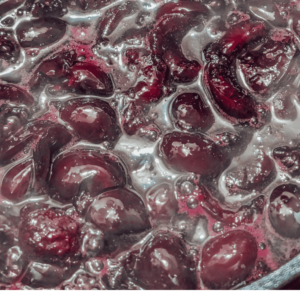 Fresh cherries boiling in syrup for homemade cherry jam.