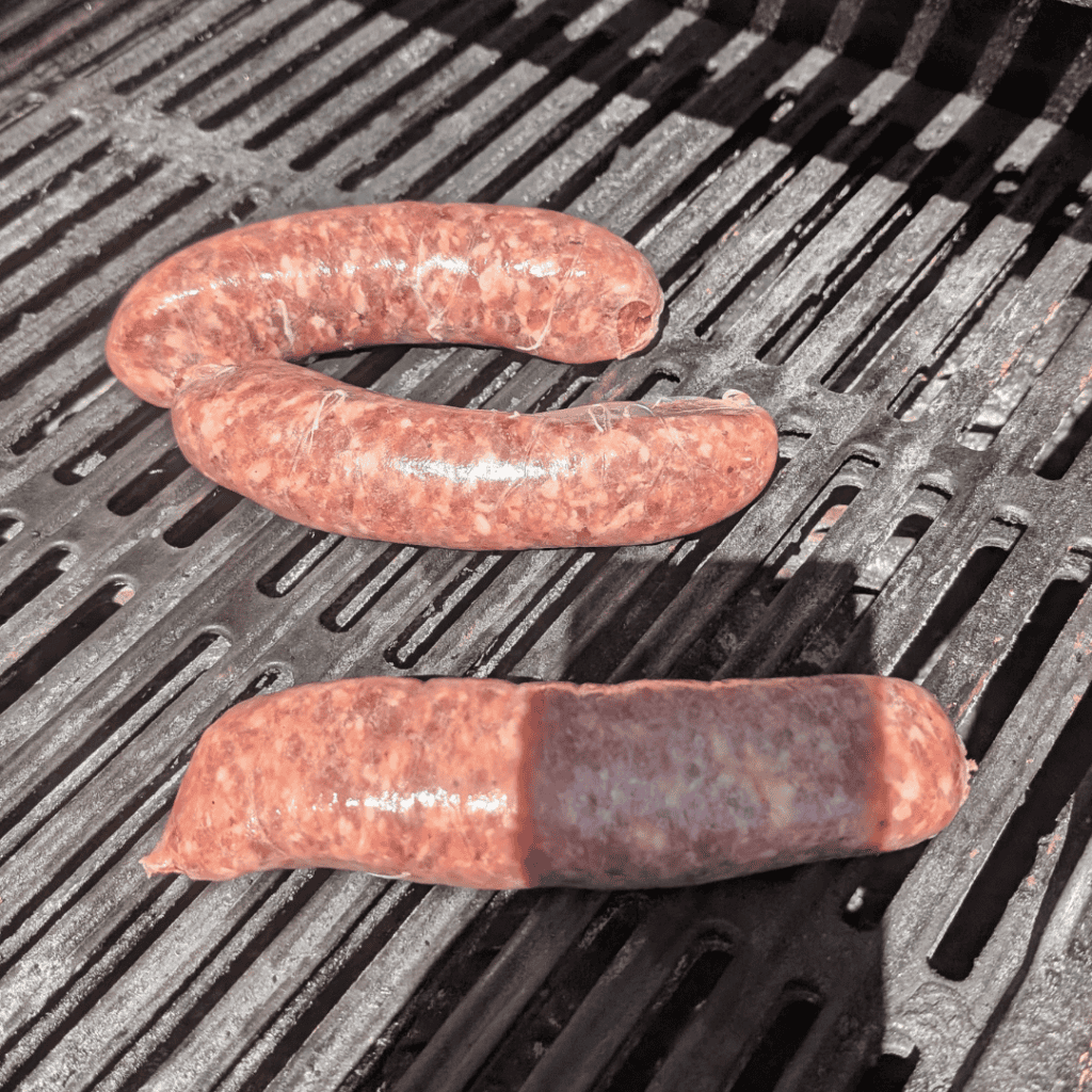 Grilled sausage links on a barbecue grill grate.