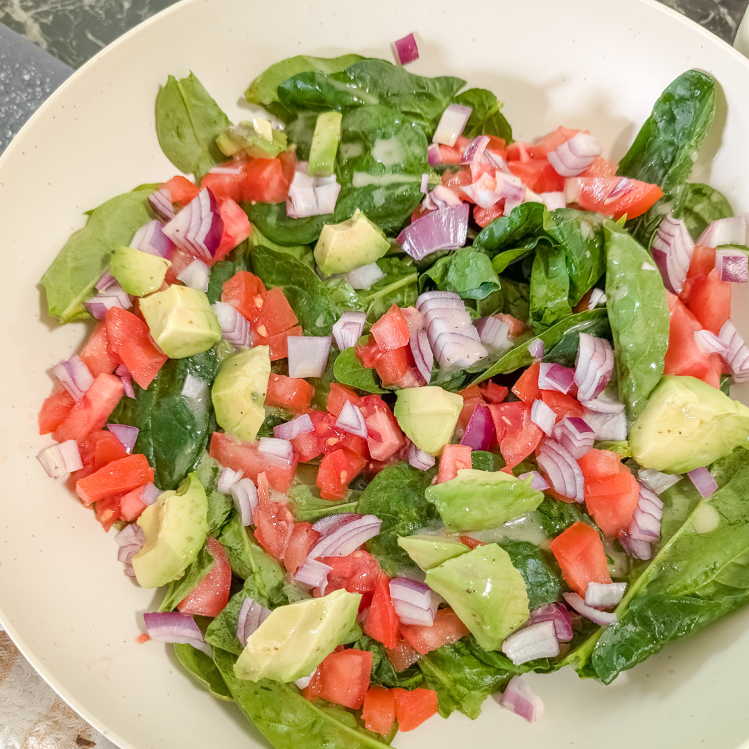 Healthy spinach salad with tomatoes, onions, and avocado for nutritious meals.