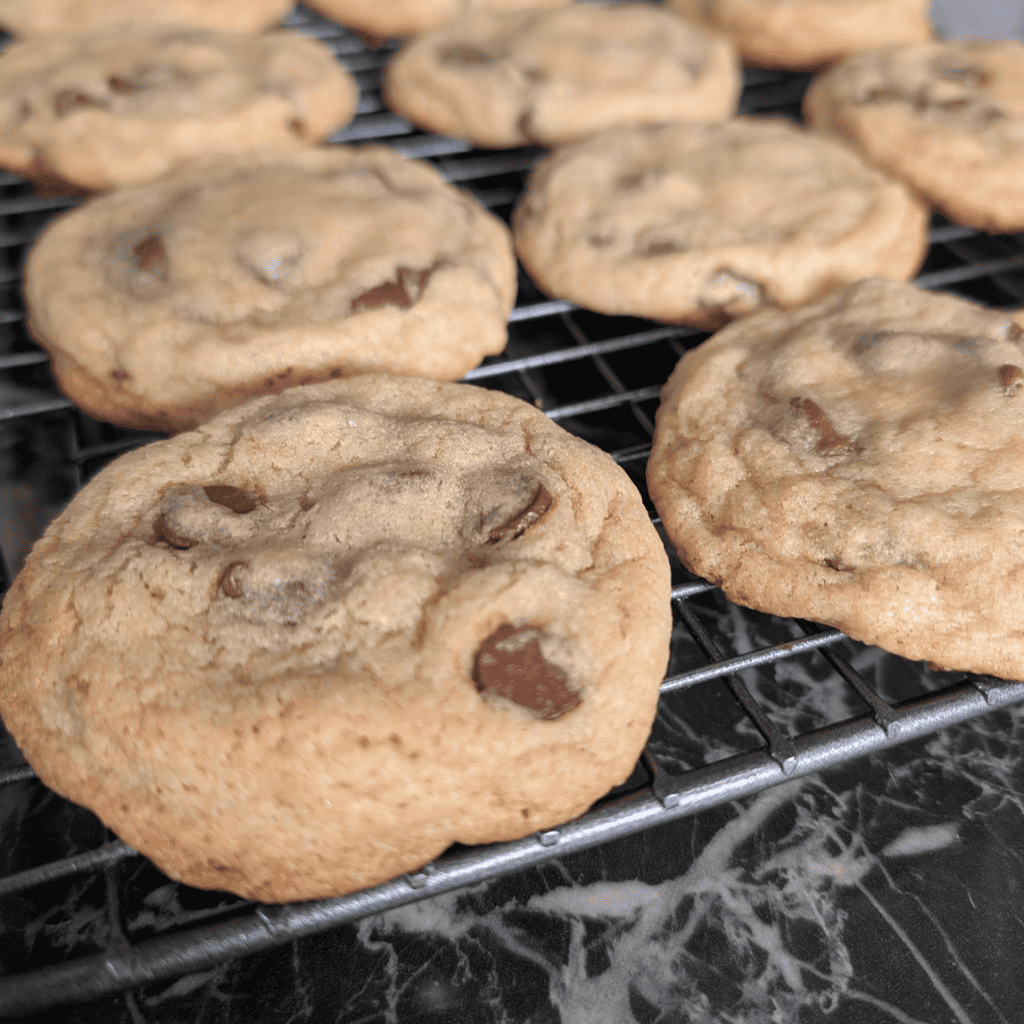 Freshly baked thick and soft chocolate chip cookies cooling on a wire rack.