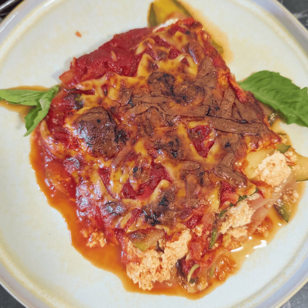 Close-up of beef enchiladas with cheese and sauce on a plate.