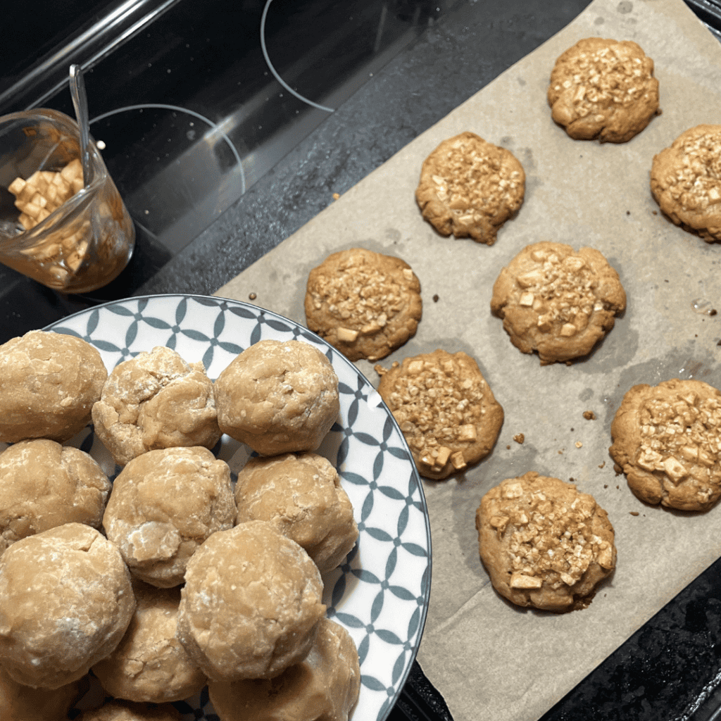 rolled cookie dough balls oversized on plate next to baked cookies on cookie sheet