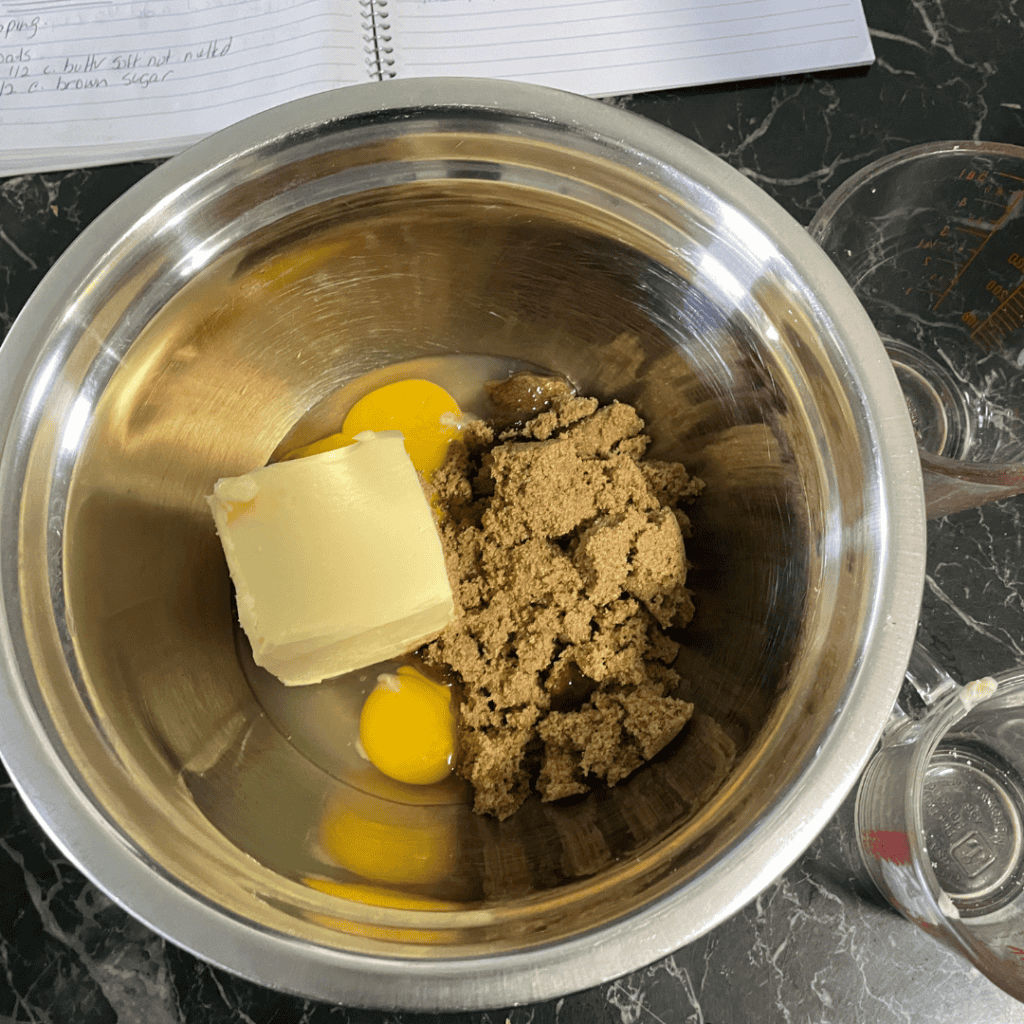 butter sugar egg in stainless mixing bowl notebook in background