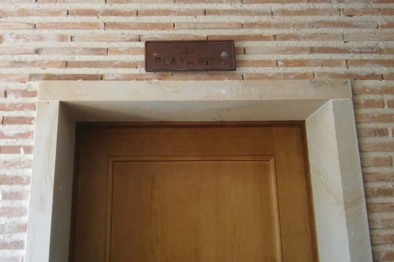 Puerta de madera en marco de piedra con cartel de cerradura en pared de ladrillos.