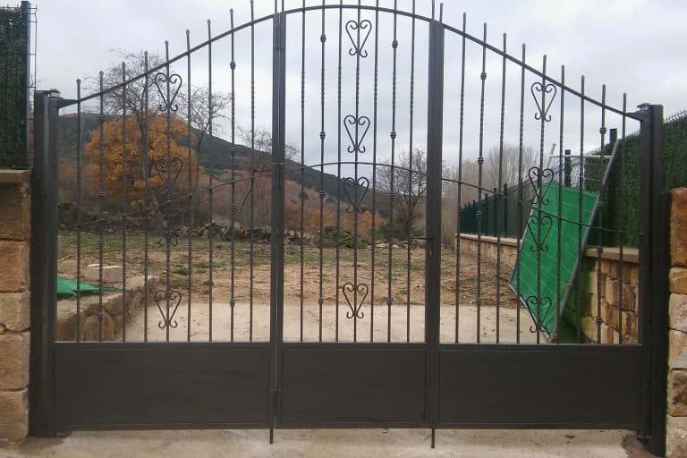 Puerta de hierro forjado con detalles en corazones, ideal para cierre de propiedades.
