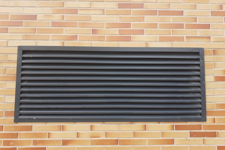 Rejilla de ventilación negra para ventilación o aire acondicionado en pared de ladrillo.