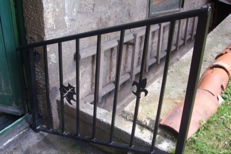 Barandilla de hierro negro con detalles decorativos en la entrada de una vivienda.