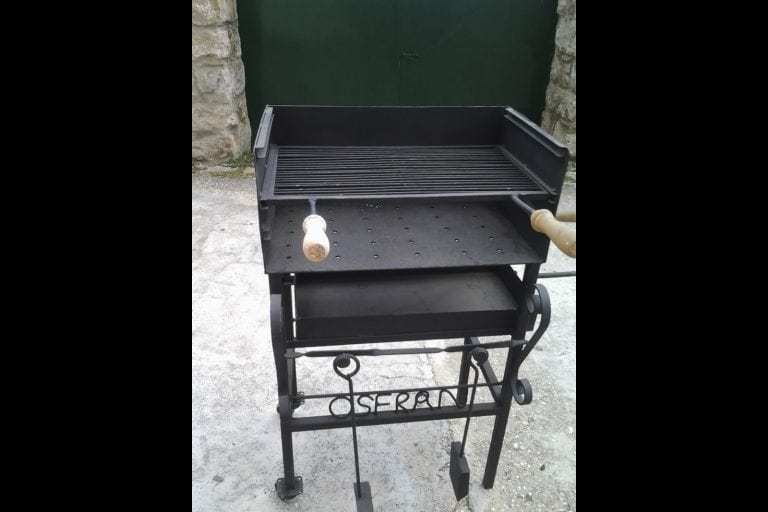 Barbacoa de hierro negra con aspas y asas de madera, ideal para parrilladas y eventos al aire libre.