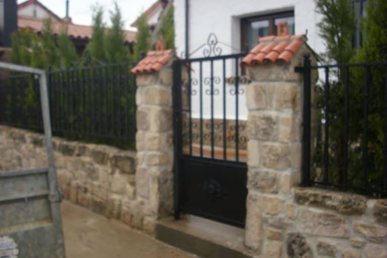 Puerta de hierro y piedra, instalación profesional en Cerrajería Osfran para seguridad y estética.
