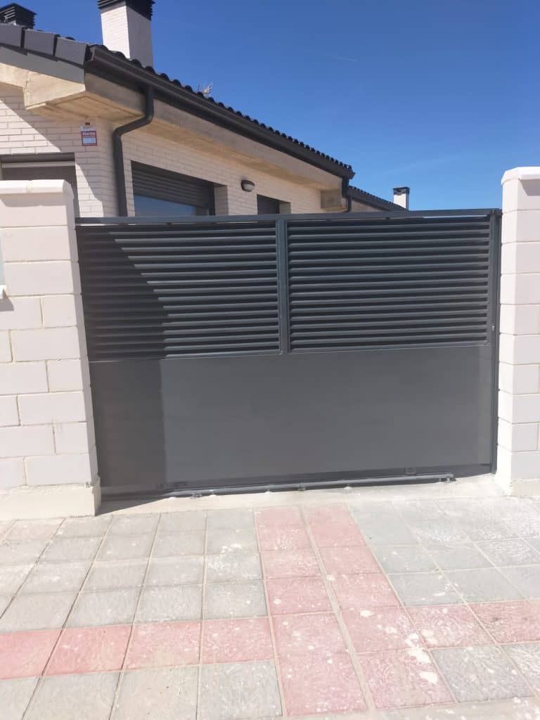Puerta automática de aluminio negro en fachada residencial, ideal para control de acceso y protección.