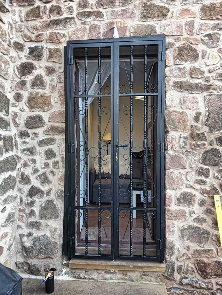 Puerta de seguridad de hierro con rejas decorativas para ventanas, protección y estilo.