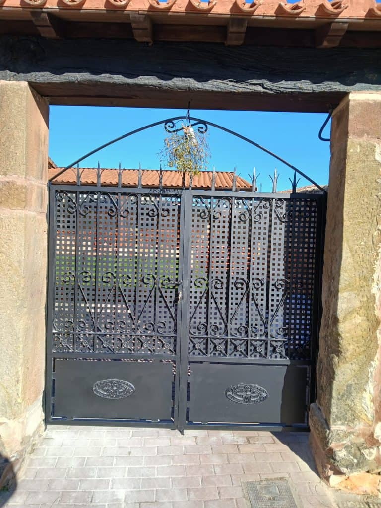 Puerta ornamental de hierro negra en entrada de casa, diseño elegante y resistente.