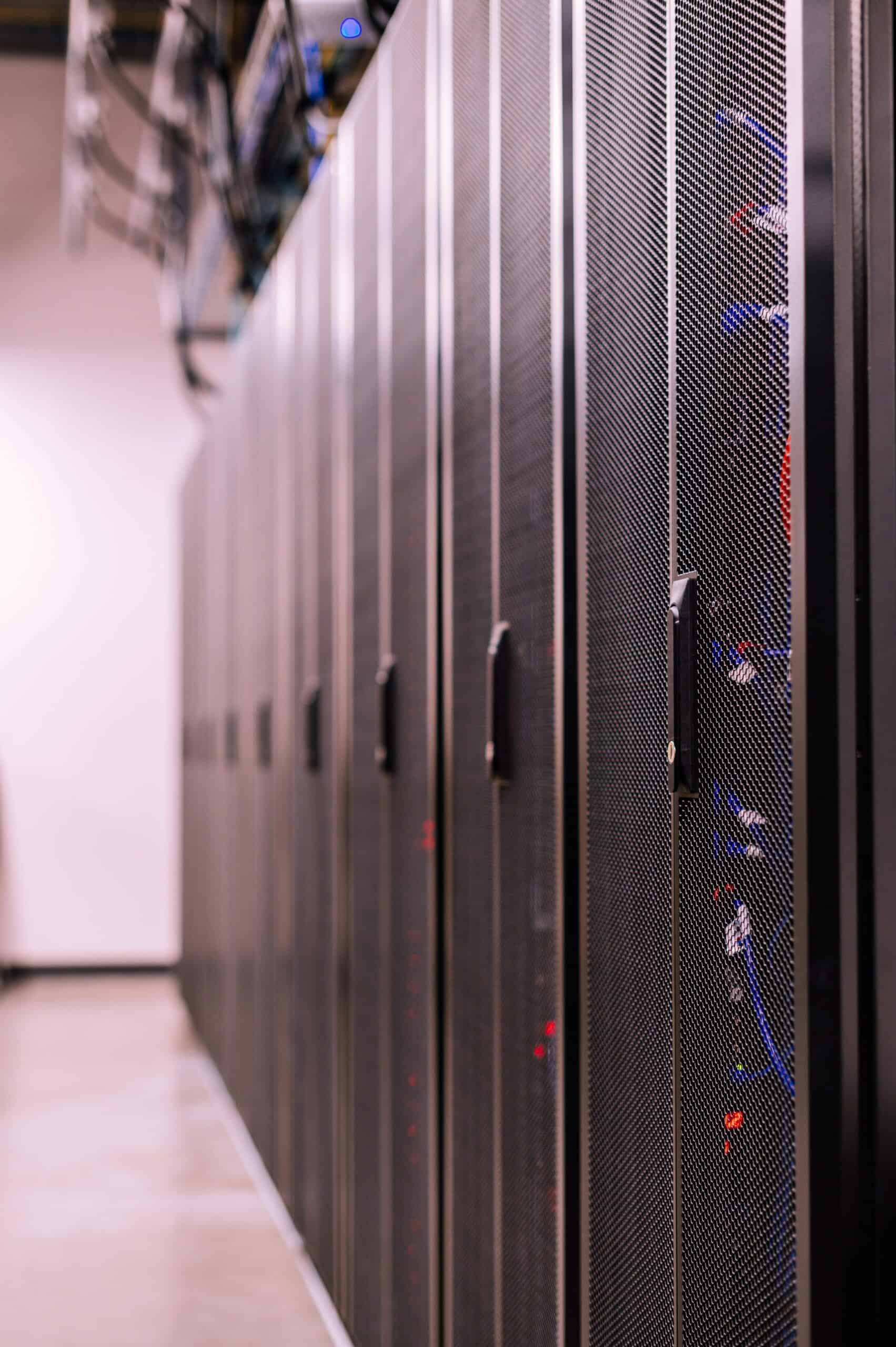 A row of black server racks in a data center, with visible cabling and handles, situated on a polished concrete floor—ideal for secure ColdFusion hosting.