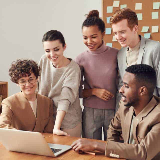 Diverse team collaborating on a project with laptop at CFSH, fostering innovation and teamwork.