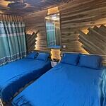 Cozy wooden cabin bedroom with blue bedding and unique wall design, perfect for romantic getaways.