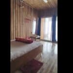 Cozy wooden hotel room with balcony, bed, and natural lighting at Check In Cherish.