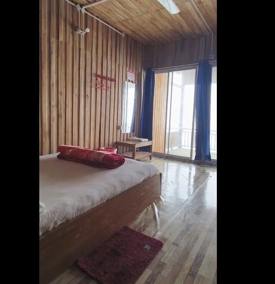 Cozy wooden hotel room with balcony, bed, and natural lighting at Check In Cherish.