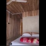 Cozy wooden bedroom with simple decor, white pillows, and red blanket for a peaceful stay.