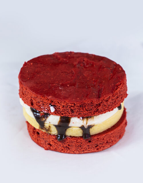 Red Velvet Cheesecake Sandwich with chocolate drizzle and creamy filling.