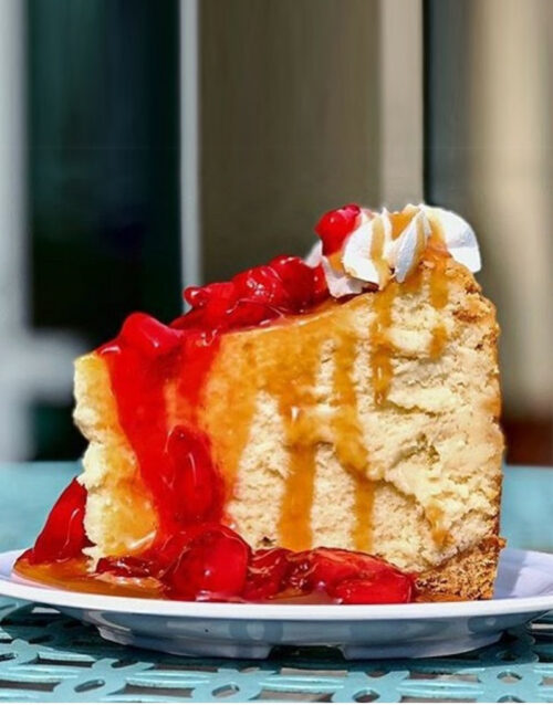 Delicious traditional cheesecake slice topped with cherry compote and whipped cream. Perfect for des.