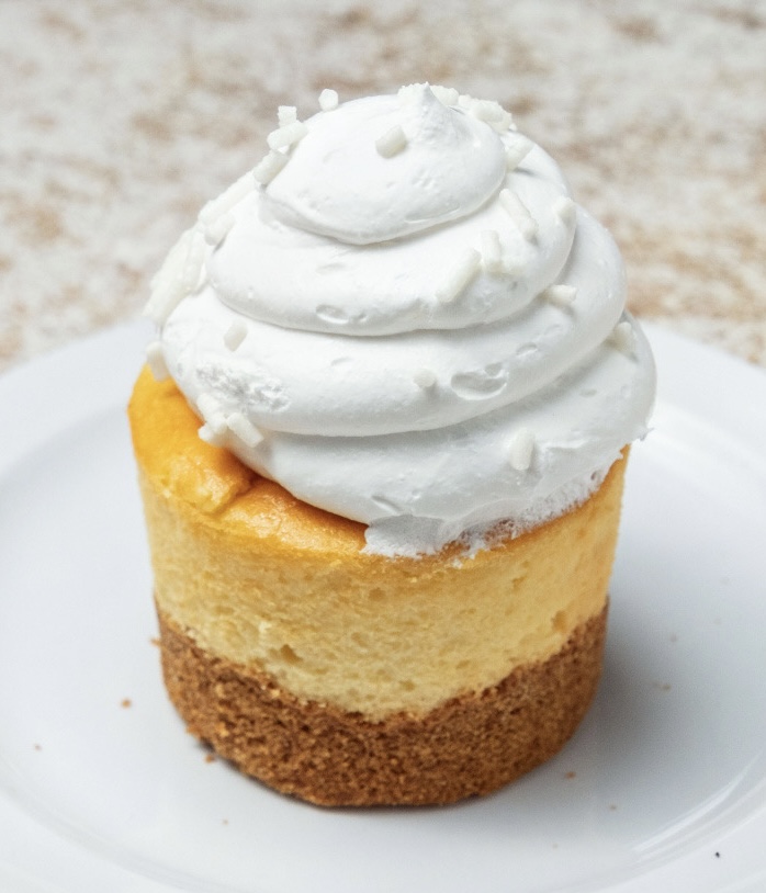 Delicious traditional cheesecake topped with whipped cream, perfect for individual servings.