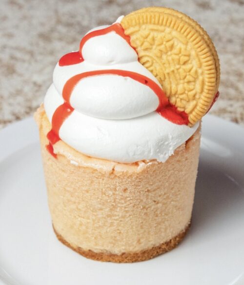 Delicious strawberry cheesecake topped with whipped cream and a cookie.