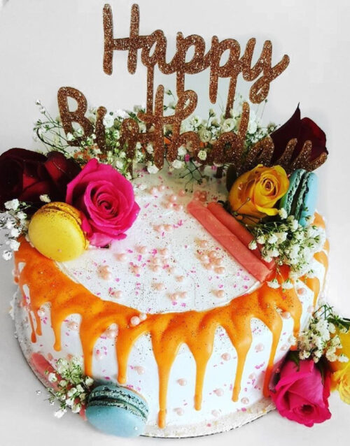 Birthday cake with colorful flowers and macarons.