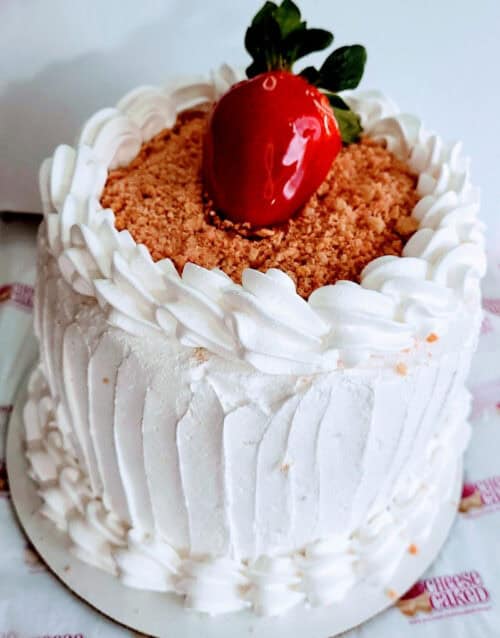 Delicious strawberry cheesecake topped with whipped cream and crumble, perfect for dessert lovers.