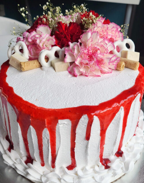 Decorative cake featuring pink and red flowers with white and red icing details.