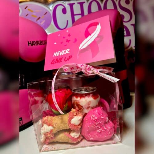 Pink breast cancer awareness treat box with cookies, chocolates, and a motivational card.