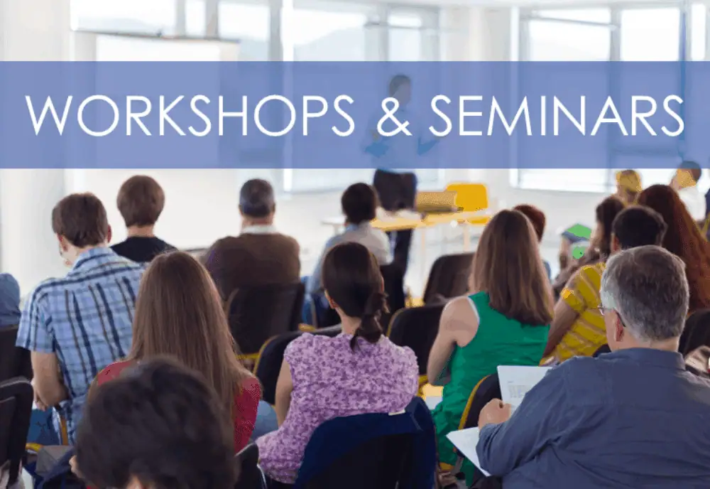 A large group attending a professional workshop or seminar, seated in a modern conference room with a presenter at the front, illustrating educational and networking opportunities.